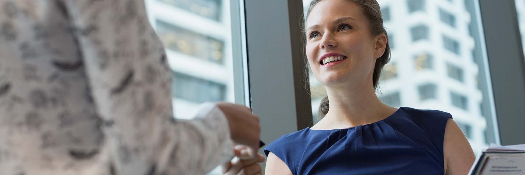 A student hands her business card to an employer at a career event.