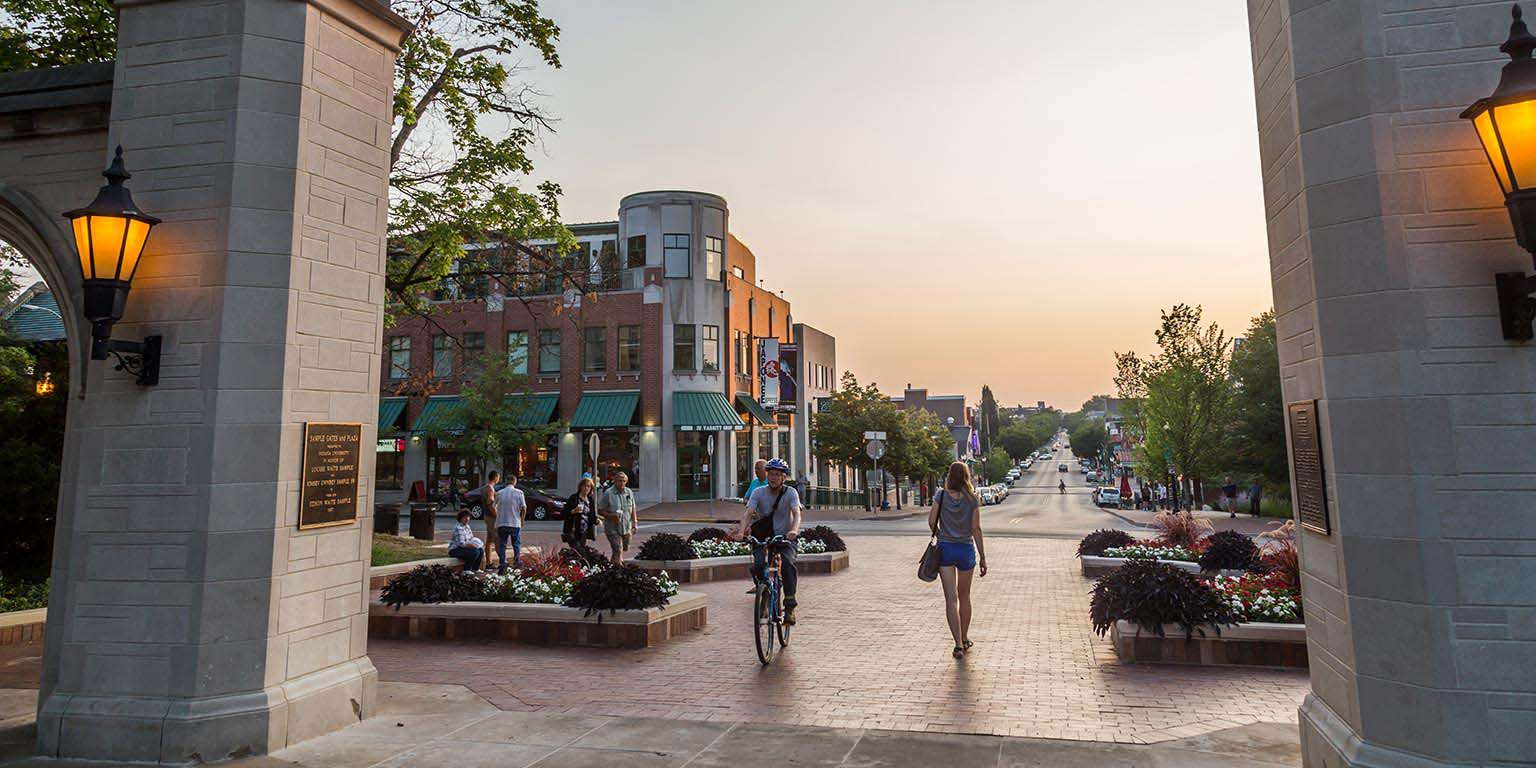 People walk and bike through the Sample Gates on the IU Bloomington campus.