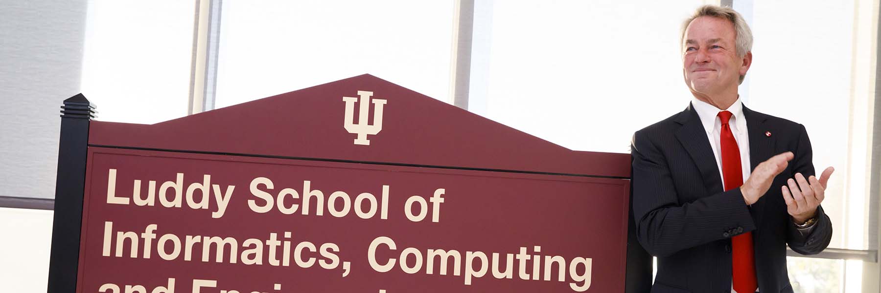 Fred Luddy standing in front of the Luddy Hall Building sign